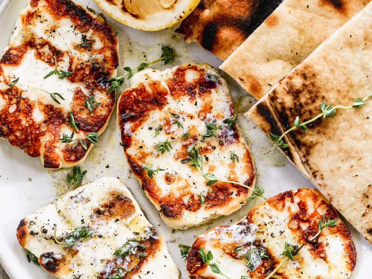 a plate with grilled halloumi cheese with herbs and lemon