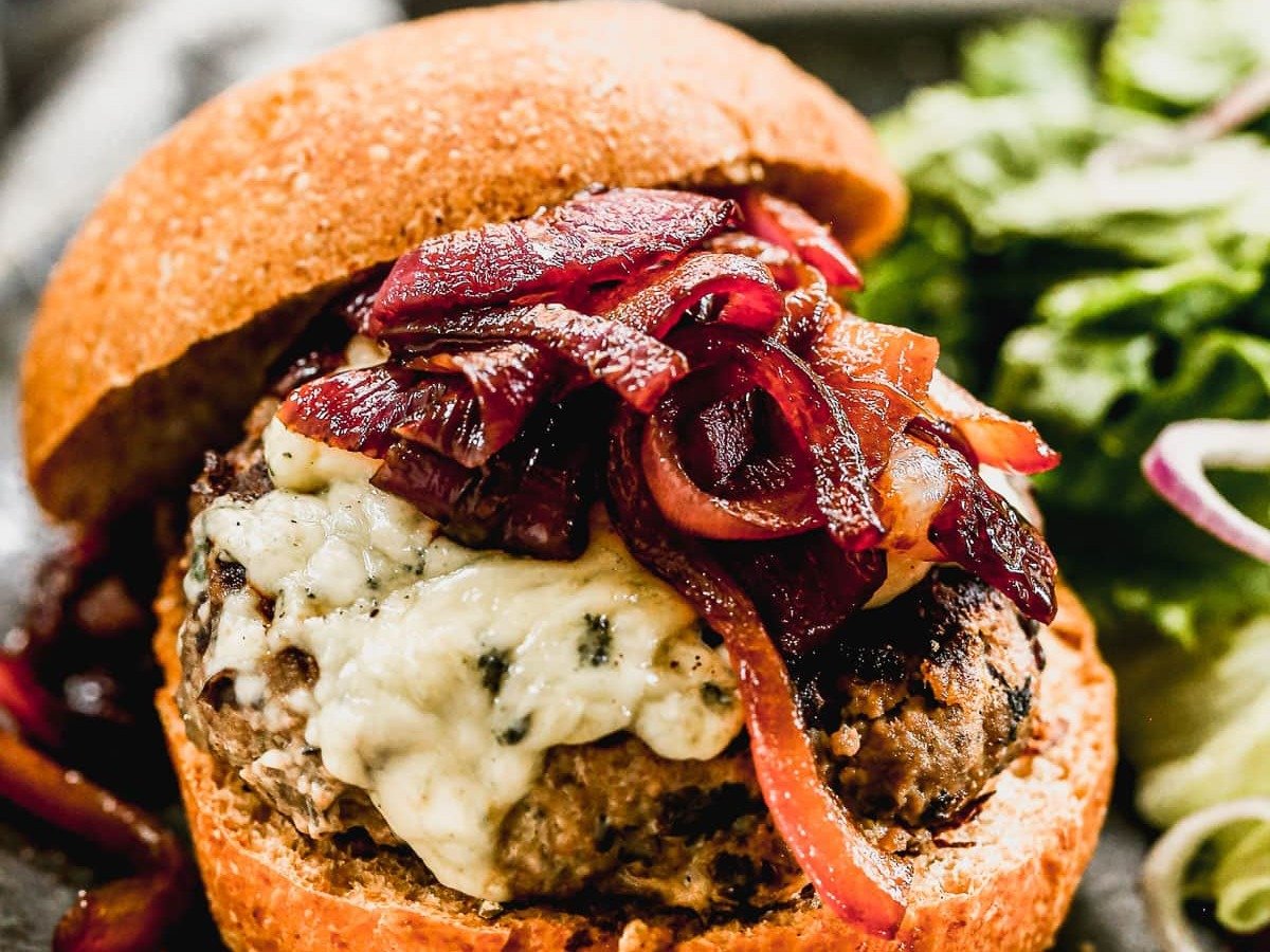 Blue Cheese Burger made with black beans and lean beef topped with caramelized onion jam on a plate with greens