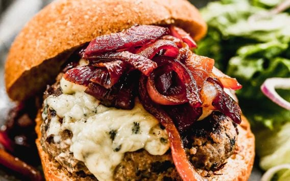 Blue Cheese Burger made with black beans and lean beef topped with caramelized onion jam on a plate with greens