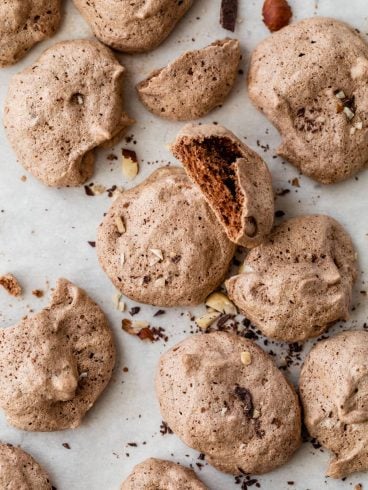 Easy Chocolate Meringue Cookies with cocoa powder and hazelnuts on a parchment-lined baking sheet
