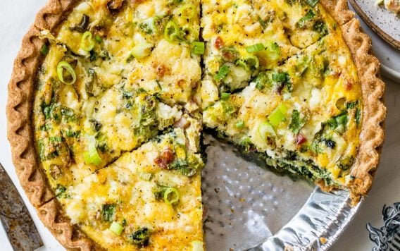 Easy quiche with spinach, cheese, and ham in a store bought pie crust with a slice cut out