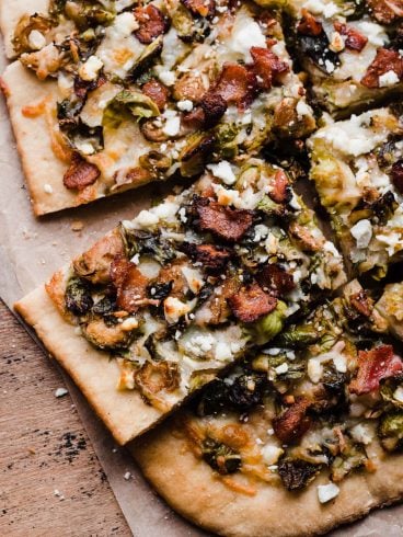 A close up of Brussel Sprouts Bacon Pizza sliced on parchment paper