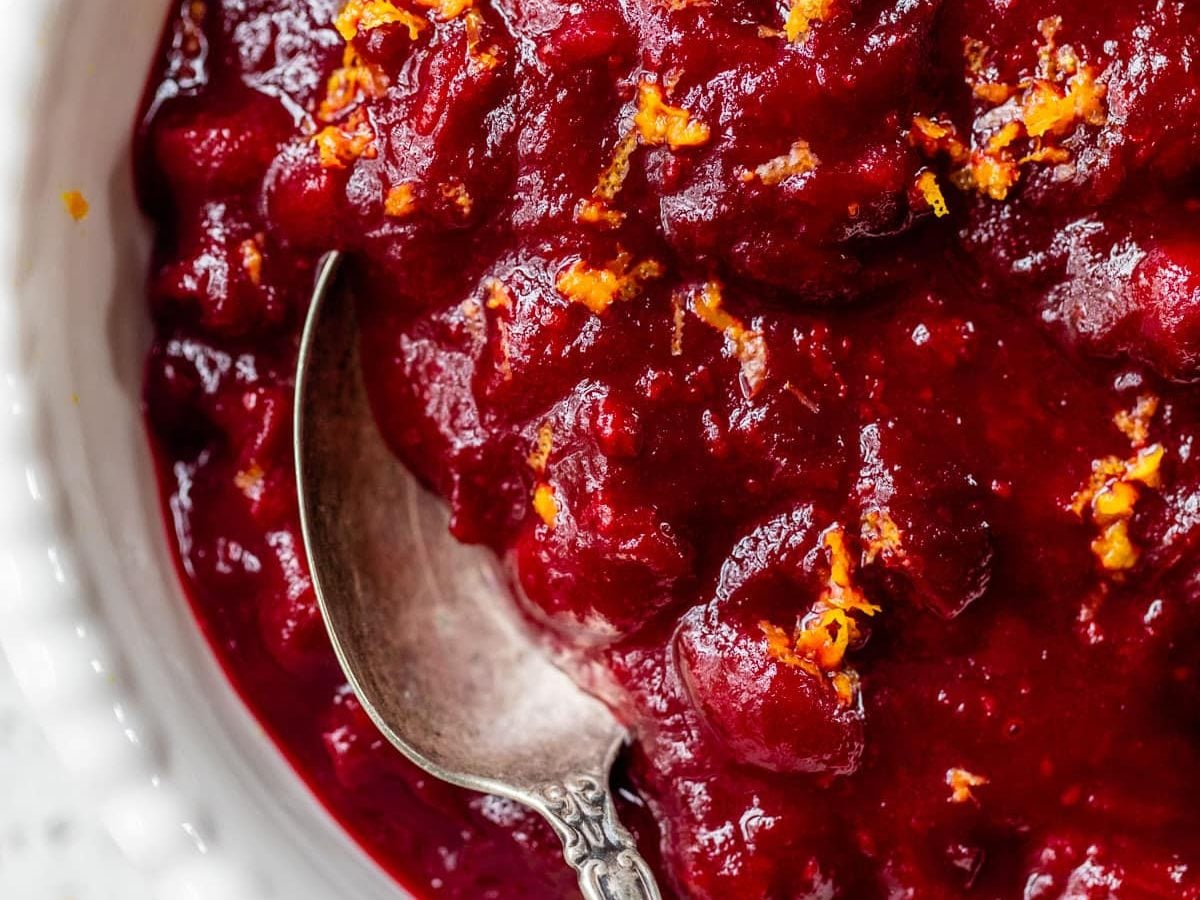 Cranberry sauce with orange juice and cinnamon in a bowl with a spoon