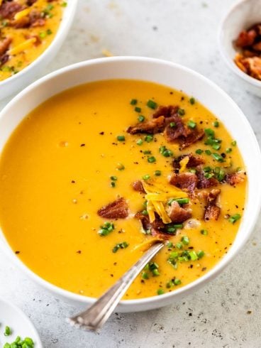 A bowl of Wisconsin potato cheese soup topped with bacon and chives