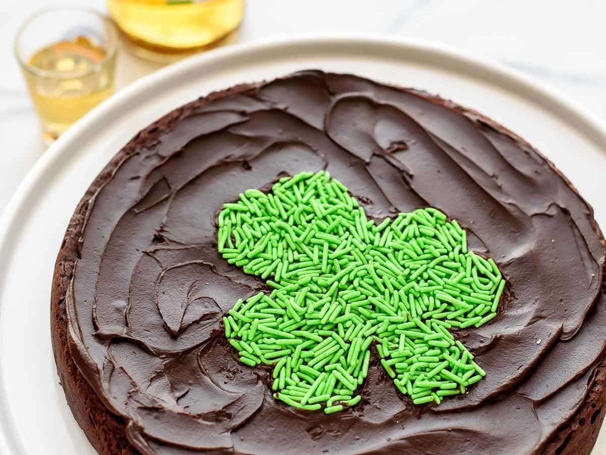 Chocolate, booze and sprinkles! A decadent, rich flourless chocolate cake with WHISKEY. Includes FREE PRINTABLE to make the cute sprinkle shamrock on top. A must make St. Patrick's Day dessert! Easy, gluten free, and so delicious. @wellplated