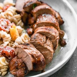 juicy grilled pork tenderloin slices on a plate with pasta salad