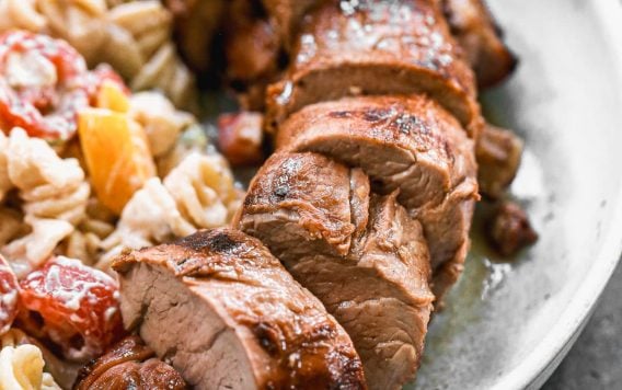 juicy grilled pork tenderloin slices on a plate with pasta salad