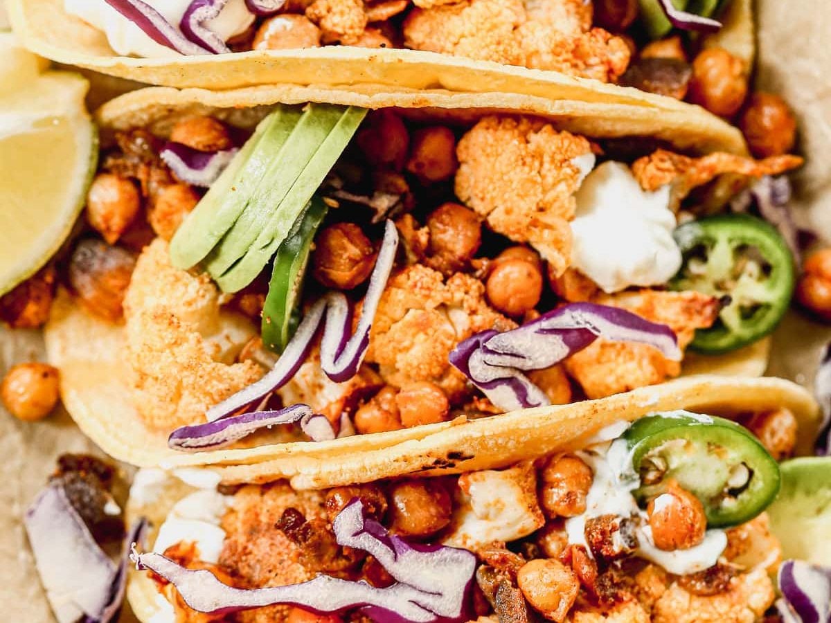 Crispy Cauliflower Tacos with chickpeas topped with avocado, jalapeno, and red cabbage