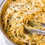 A stainless steel pot full of pasta with pumpkin pasta sauce