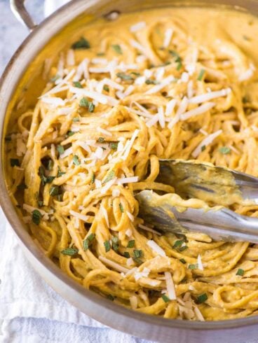 A stainless steel pot full of pasta with pumpkin pasta sauce