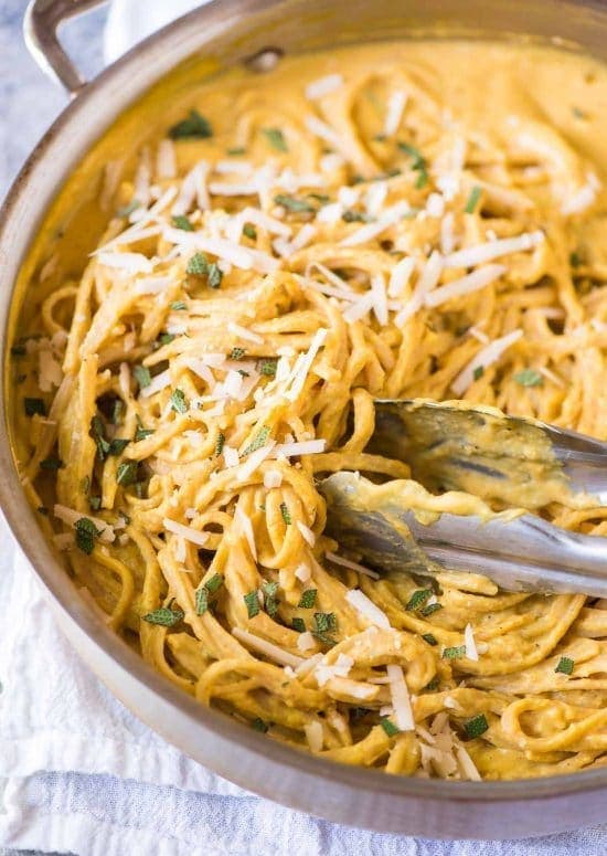 A stainless steel pot full of pasta with pumpkin pasta sauce