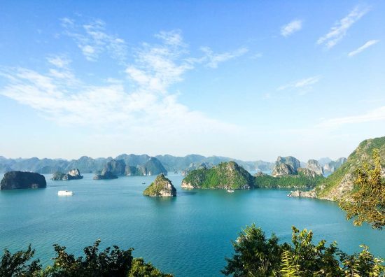 A body of water with small islands with Ha Long Bay in the background.