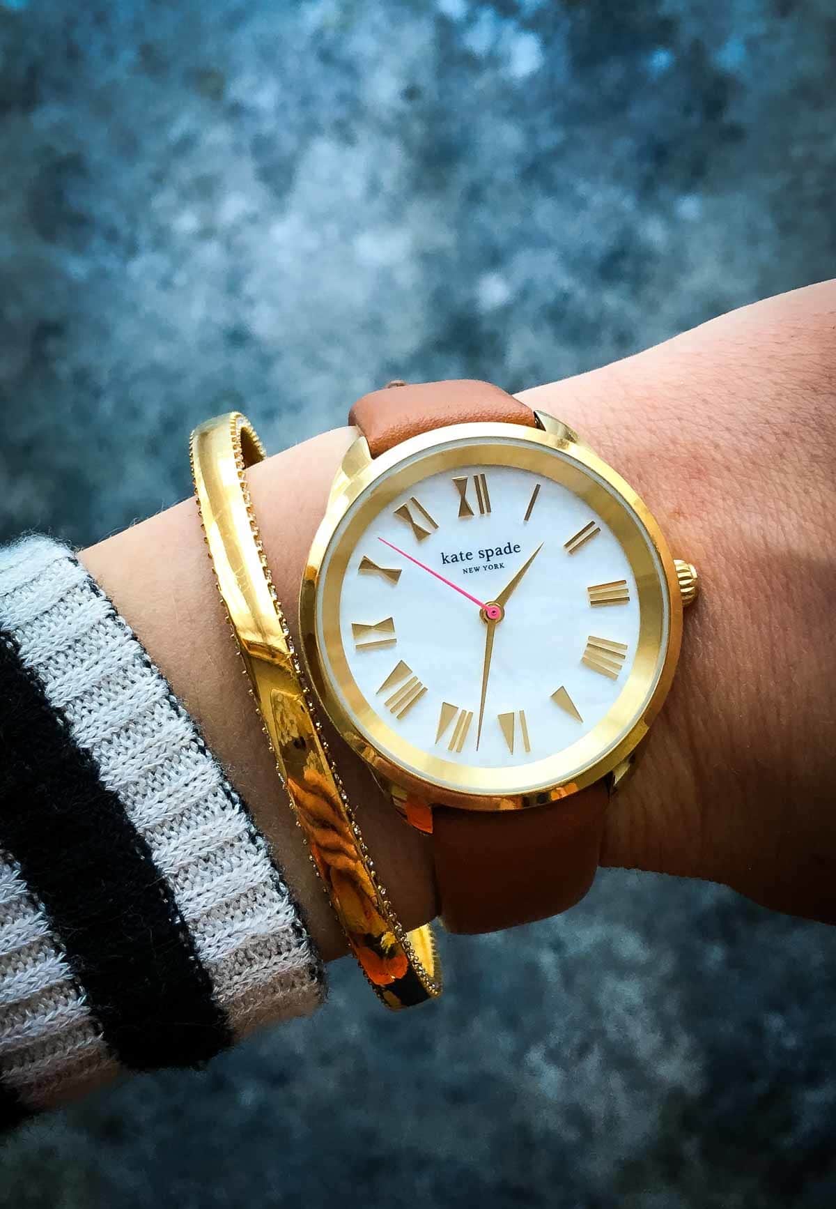 A woman's wrist with a Kate Spade watch and bracelet