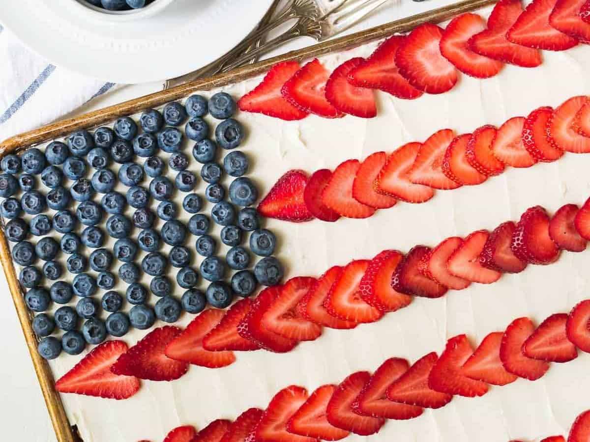 American Flag Cake. Made with REAL ingredients! From scratch fluffy yellow sheet cake, topped with Greek yogurt cream cheese frosting, fresh strawberry, and blueberry to look like an American flag. The perfect patriotic dessert recipe for the Fourth of July, Memorial Day, and Labor Day. Recipe at wellplated.com | @wellplated