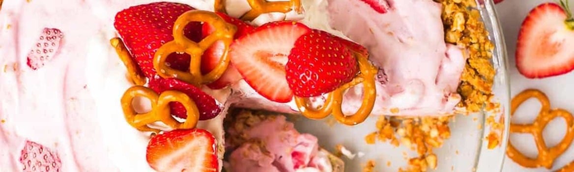 Strawberry pretzel pie with a pretzel crust, topped with fresh strawberries and pretzels, with two forks in a slice.
