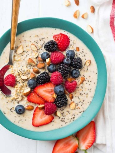 A blue bowl of overnight steel cut oats with fresh berries on top