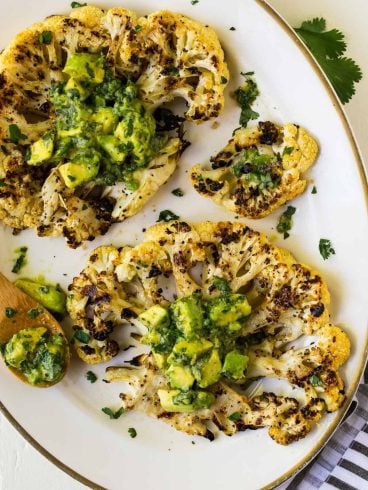 Grilled Cauliflower Steak with Avocado Herb Sauce. So delicious and filling, you won’t miss the meat! Great for easy, healthy sides or a light summer dinner.