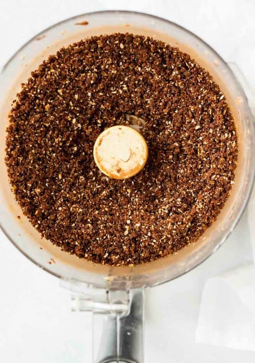 Top view of a food processor with finely ground chocolate mixture inside.
