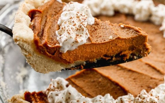 a slice of no bake pumpkin pie vegan being removed from a whole pie