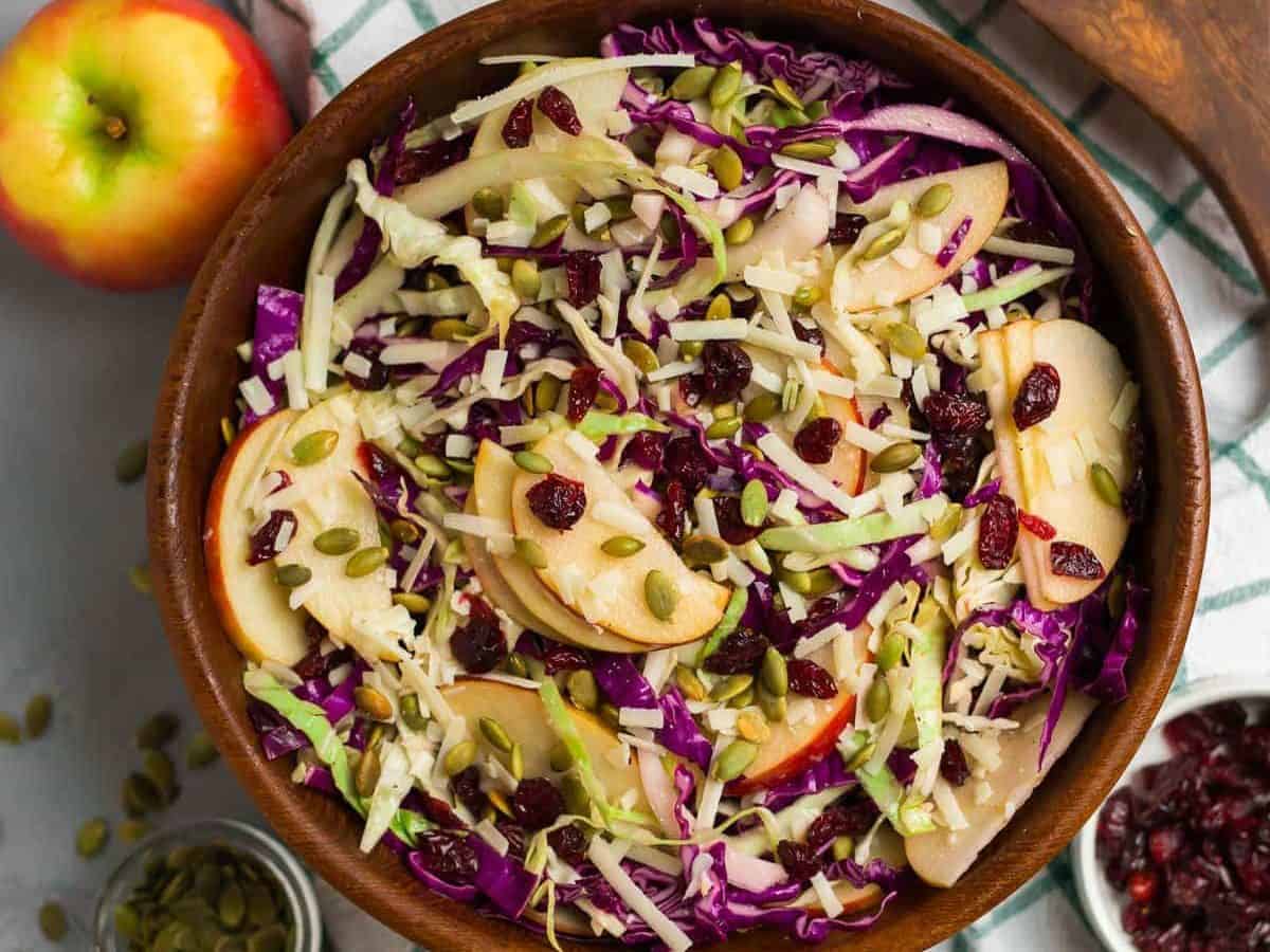 Crisp Winter Slaw with dried cranberries, cabbages, apple, and Parmesan. A healthy, fresh, and delicious coleslaw recipe that’s perfect for a Christmas or Thanksgiving side dish. Add chicken or quinoa to make it easy to pack for lunch! Lasts in the refrigerator for several days, so it’s great as a make ahead side or for meal prep.