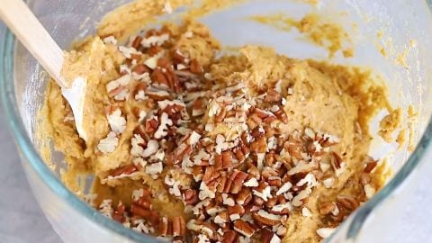Pecans added to bowl of pumpkin banana bread batter.