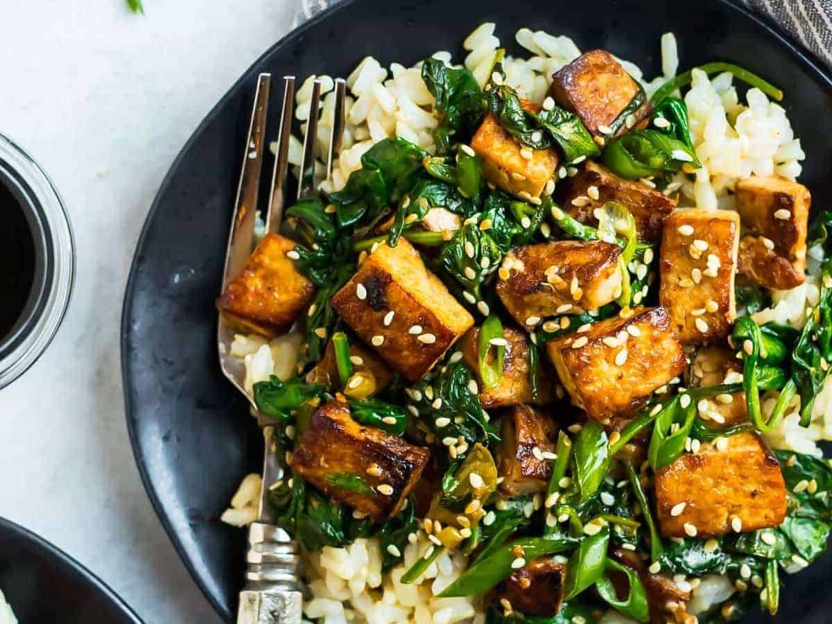 Easy Sesame Tofu Stir Fry. Crispy tofu with spinach, broccoli, or any fresh vegetables you love. This vegan recipe is packed with flavor in a simple, delicious Asian garlic ginger sauce. Serve with rice or noodles.