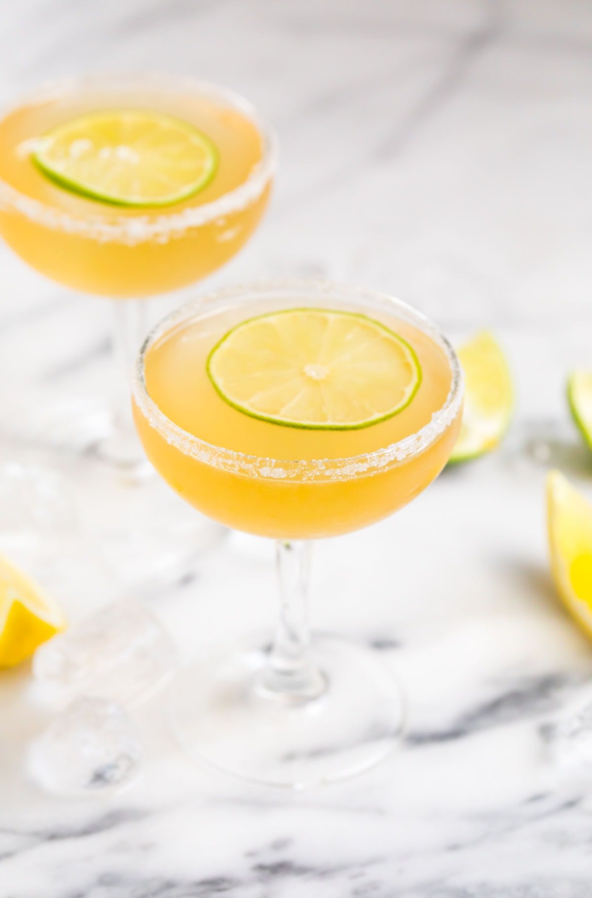 Two Italian margaritas with salted rims and lime wheels floating on top