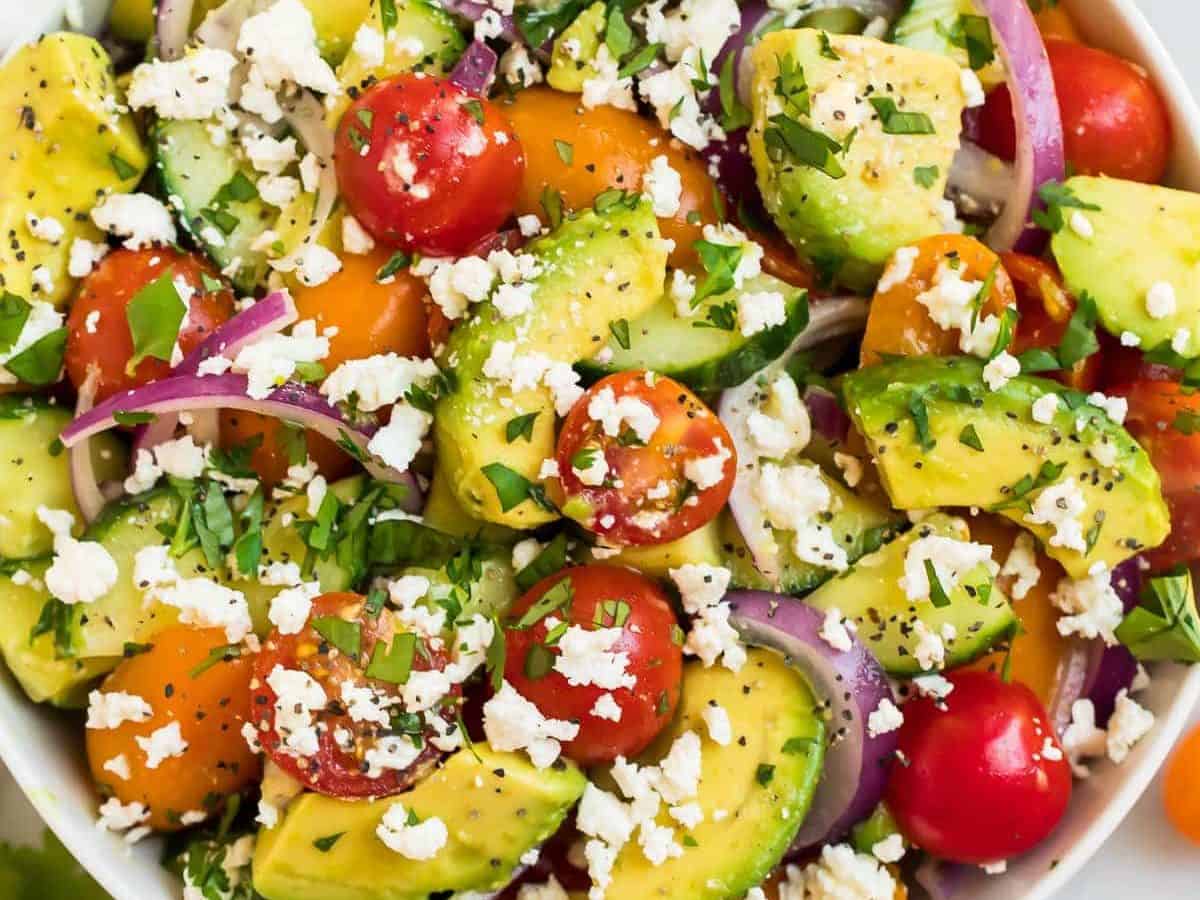 A white bowl full of avocado tomato salad