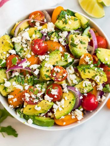 A white bowl full of avocado tomato salad