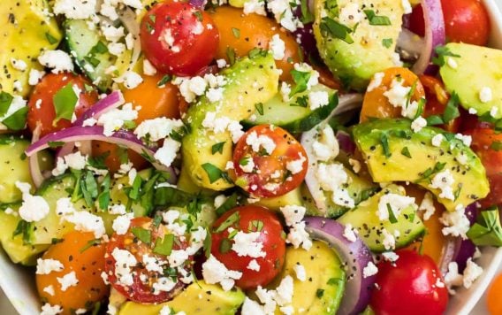 A white bowl full of avocado tomato salad