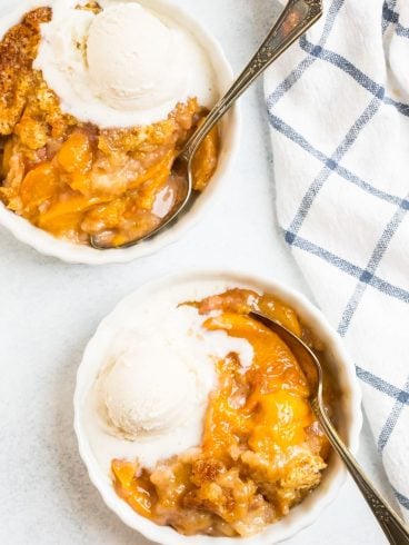 Easy Dutch Oven Peach Cobbler inside a dutch oven with fresh peaches.