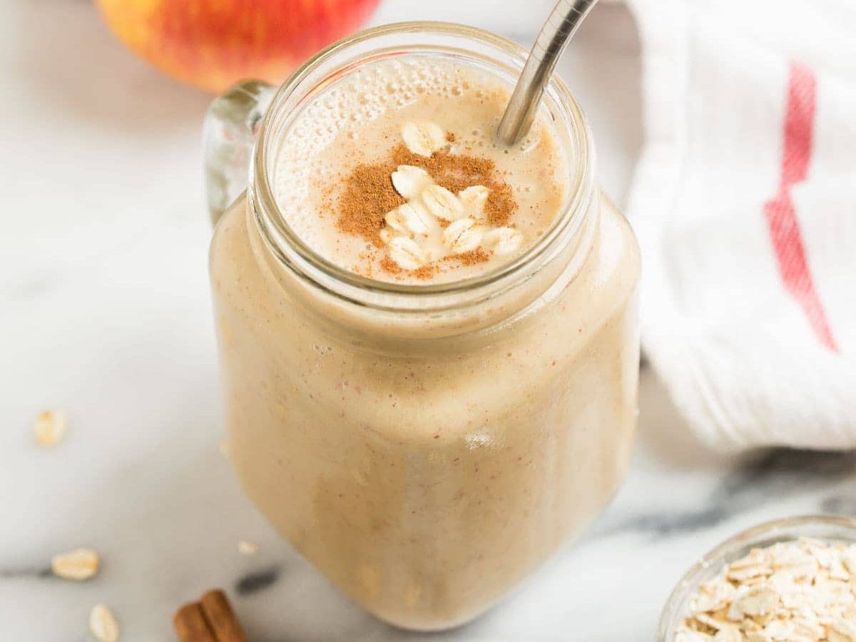 A mug with a creamy vegan apple smoothie with banana, oatmeal, and cinnamon