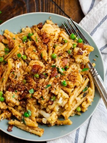 A blue plate with cauliflower pasta and bacon topping