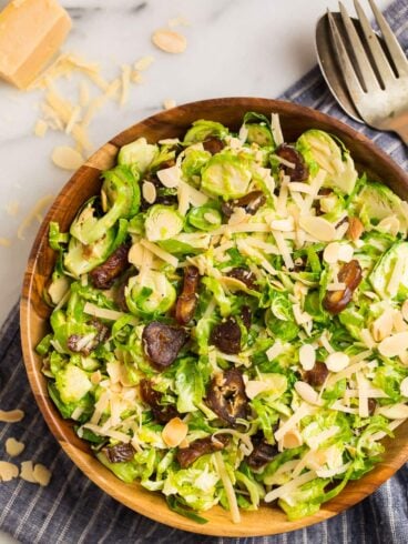 Fresh and healthy brussels sprouts slaw made with shredded brussels sprouts in a honey lemon Dijon dressing, inside of a wood bowl