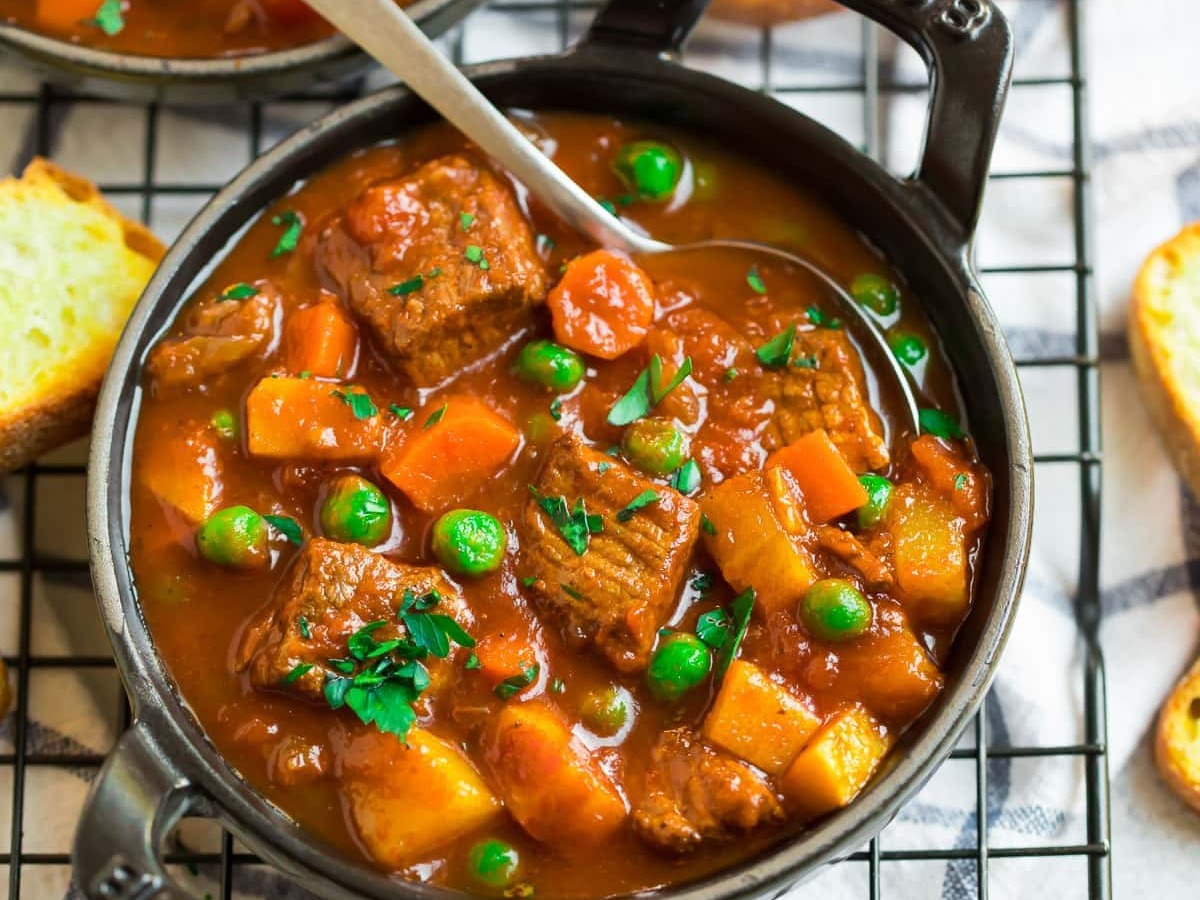 A black bowl with thick beef and vegetable soup