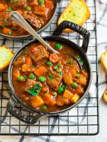 A black bowl with thick beef and vegetable soup