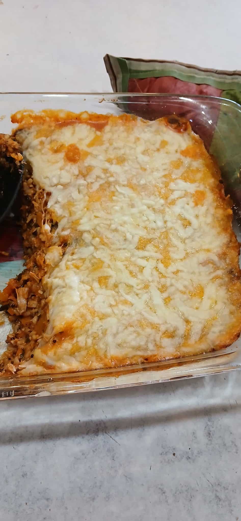 A casserole dish with a cheesy baked lasagna, partially served with a section missing from one corner.