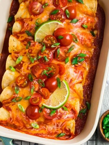 A blue casserole dish with creamy Instant Pot Chicken Enchiladas, topped with red enchilada sauce and cheese