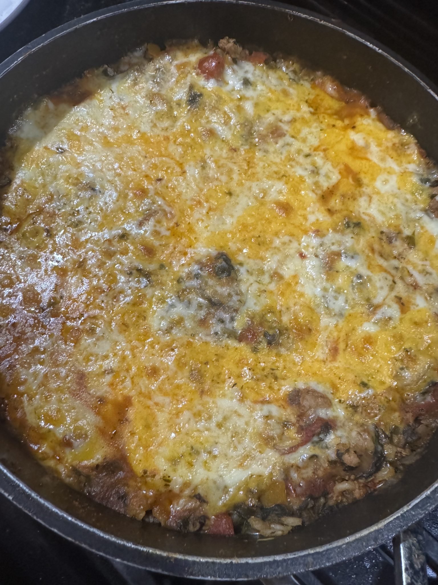 Cheesy casserole with ground meat, vegetables, and melted cheese baked in a round pan.