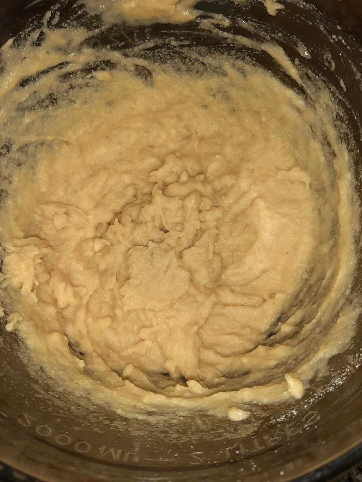 Thick, creamy batter is mixed in a glass bowl, with some batter clinging to the sides.