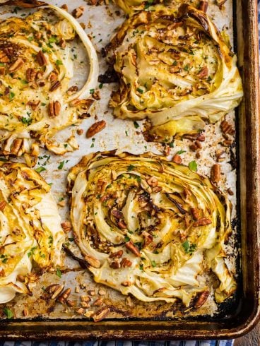 Cabbage steaks on a baking sheet with chopped nuts