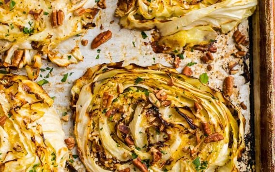 Cabbage steaks on a baking sheet with chopped nuts