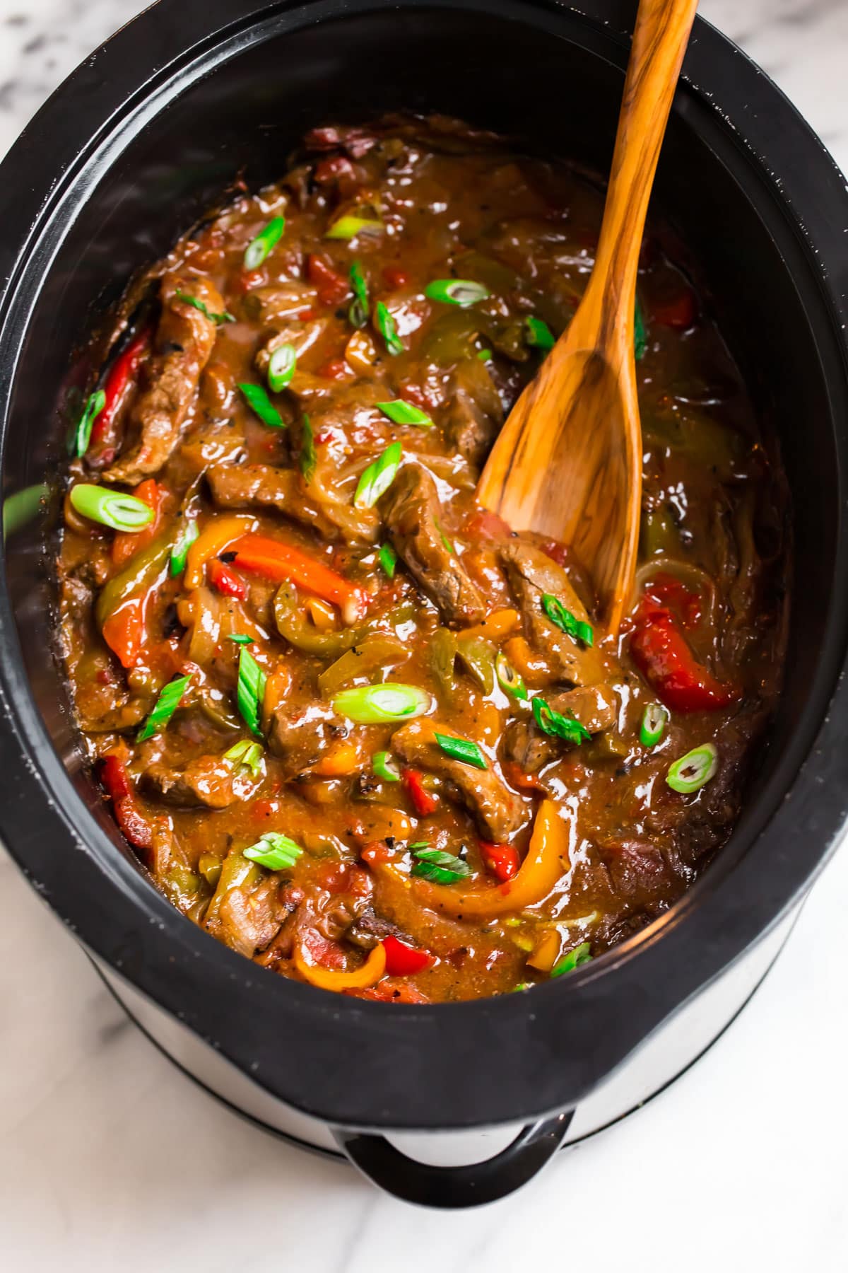 A slow cooker with beef and vegetables in a sticky Asian sauce