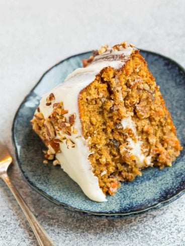 A blue plate with a slice of moist gluten free carrot cake with almond flour topped with cream cheese frosting