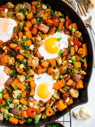 a skillet with sweet potato and sausage hash with peppers and eggs
