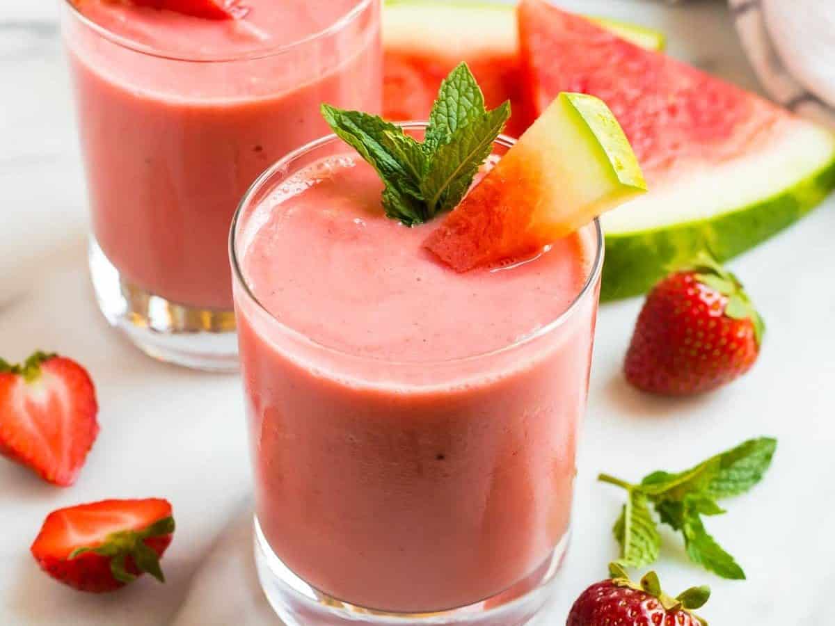 Two glasses of a creamy watermelon smoothie with strawberry and mint