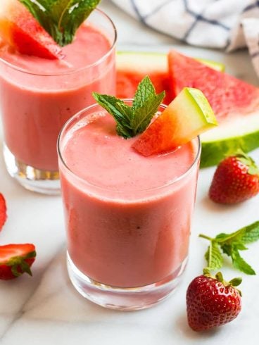 Two glasses of a creamy watermelon smoothie with strawberry and mint