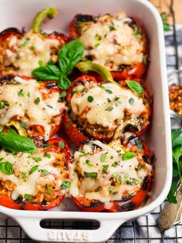 A white baking dish with healthy stuffed peppers cooked on the grill