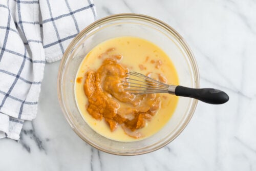 Pumpkin being whisked into wet ingredients