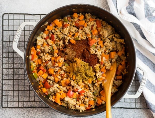 Spices being added to a Dutch oven